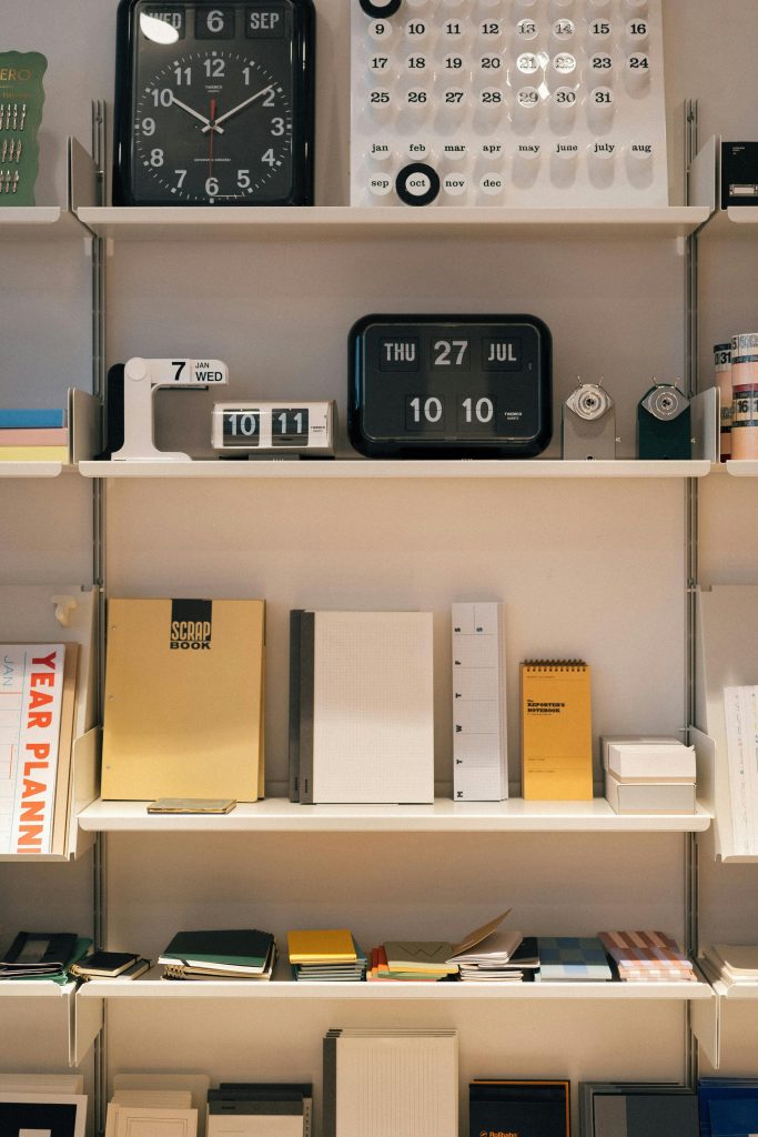 Organized shelves with clocks, calendars, and notebooks in London office.